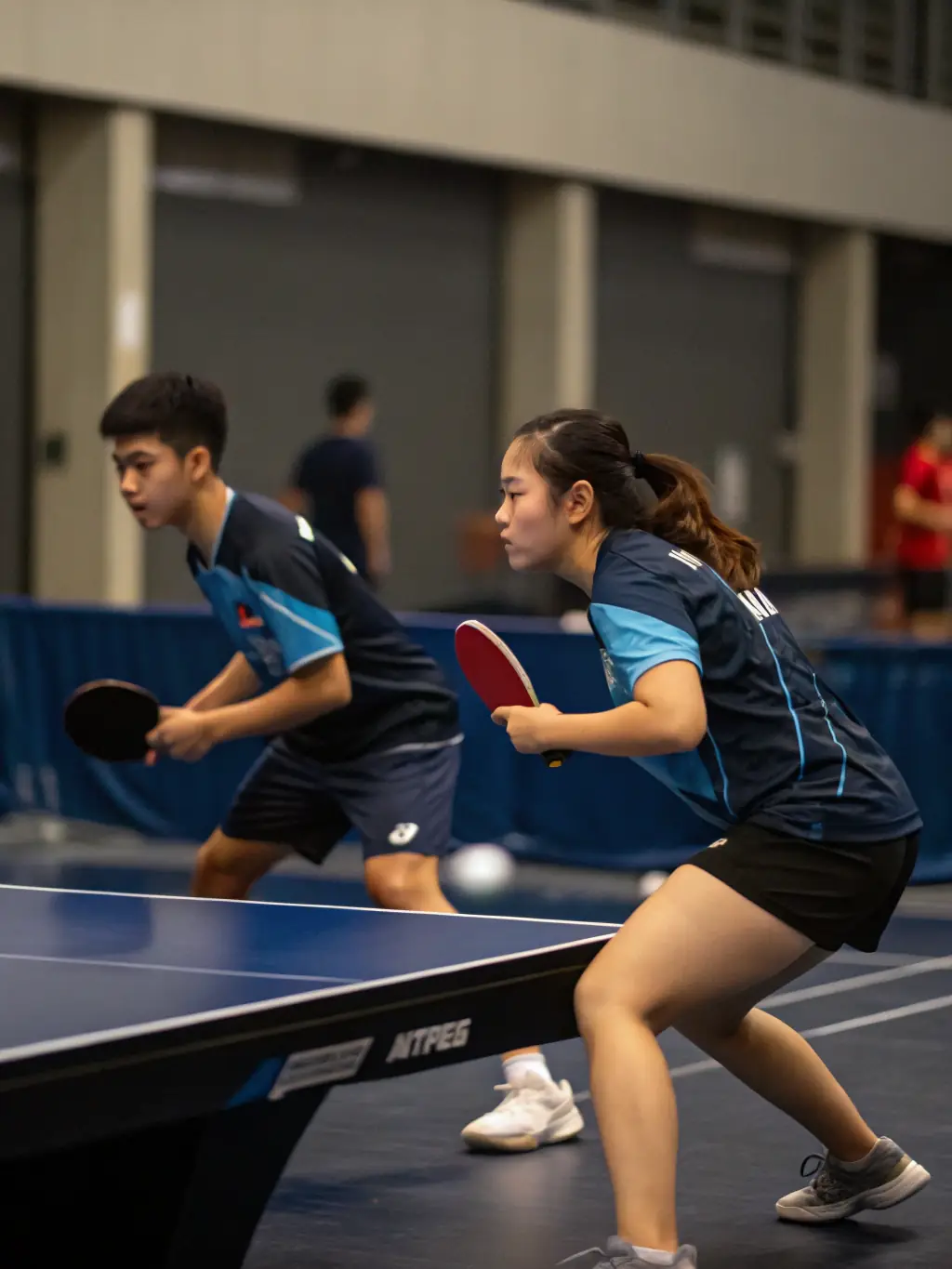 An intense table tennis match in progress, capturing the speed and precision of the sport, highlighting 3 RAQUETTES' dedication to fostering competitive spirit and skill in table tennis.